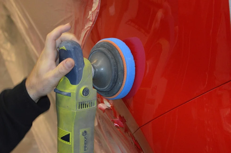 Poliermaschine mit blauem Polierpad auf rotem Autolack