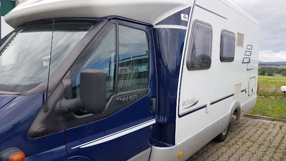 Blau-weißes Wohnmobil auf Ford-Transit-Basis mit bearbeiteter Seitenverkleidung
